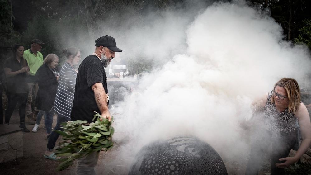 A man lights a fire during a smoking ceremony at Woolyungah. Photo: Paul Jones