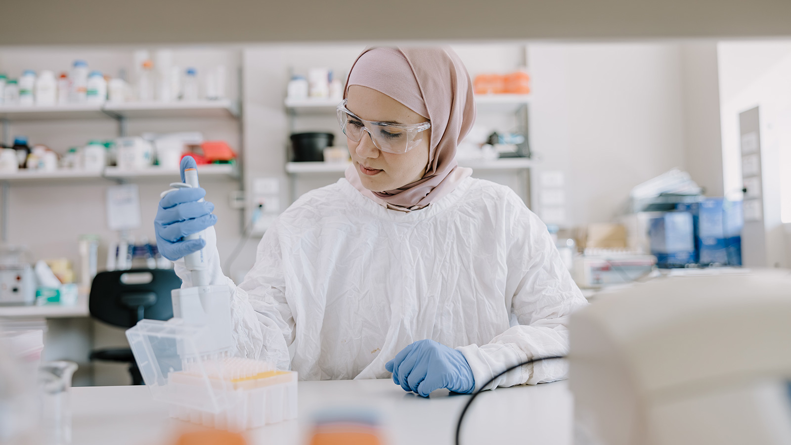 A woman is peppetting samples into test tubes in a lab.