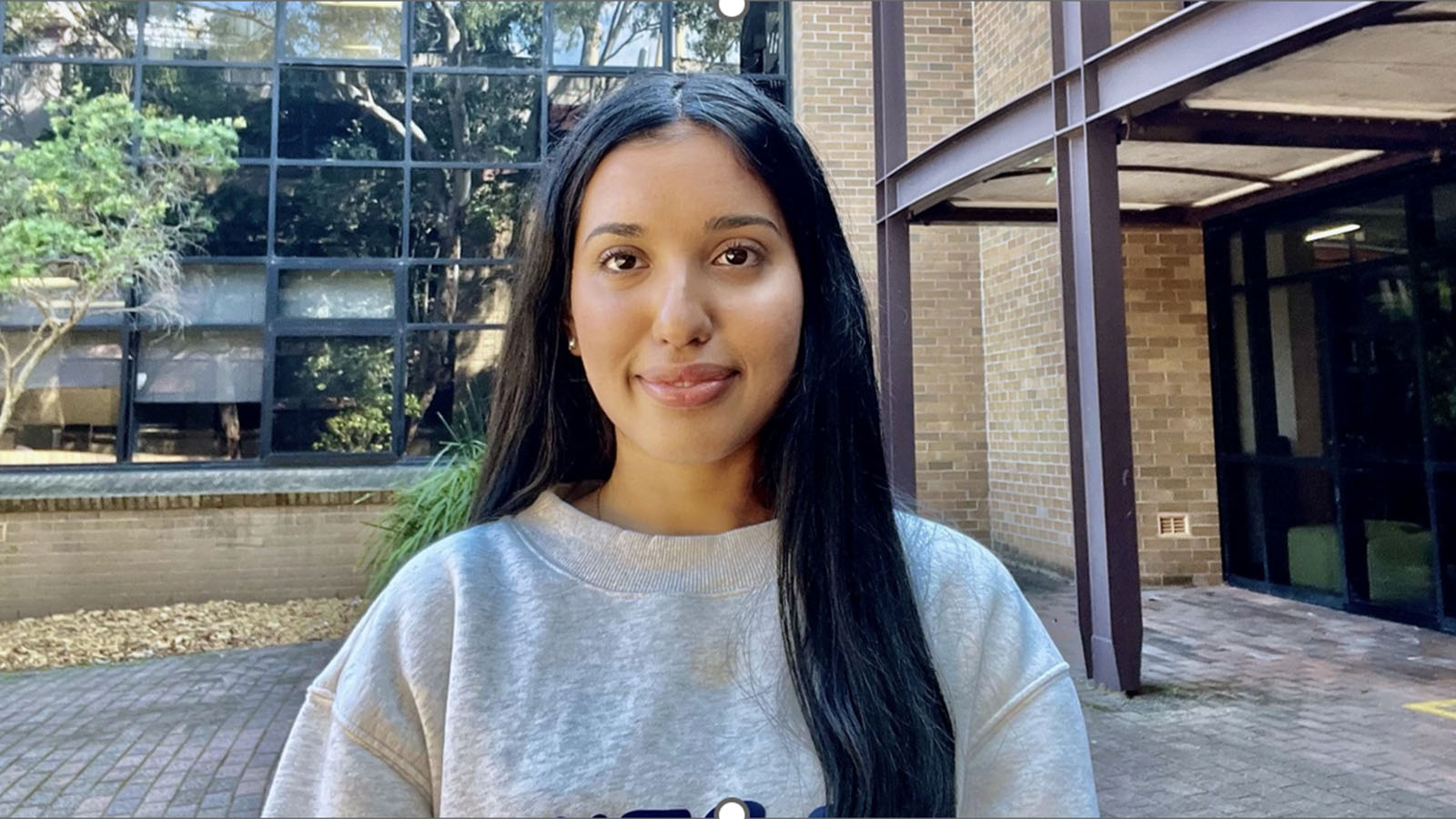 A young woman is standing outside UOW nursing building.