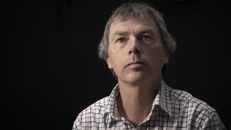 Man in plaid shirt looking up on black background