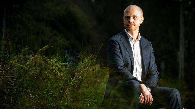 Man blue suit sitting amongst greenery