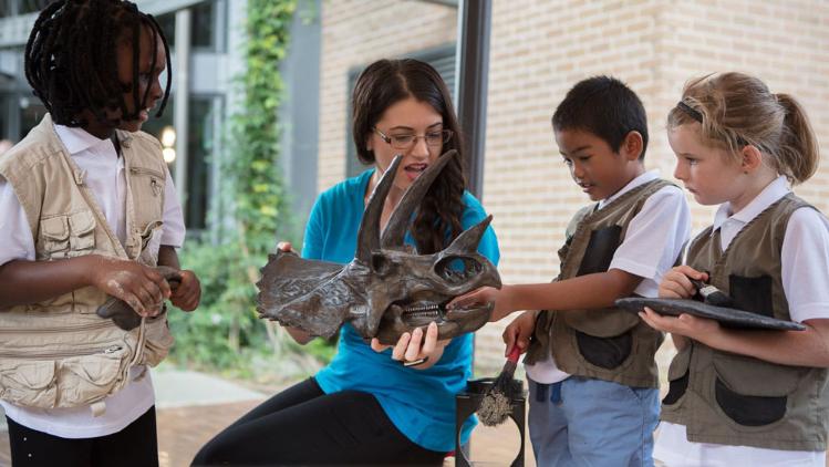 School children inspecting a model of a dinosaur skull