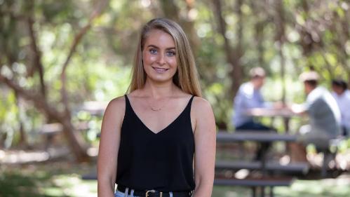 Female student posing for camera, standing in front of trees at the UOW Southern Sydney campus