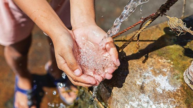 Hands of a child catching clear running water from a tap