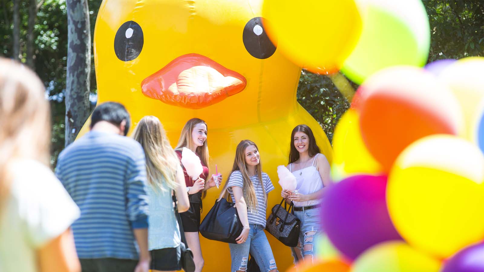 Female students stand under a yellow inflatable duck