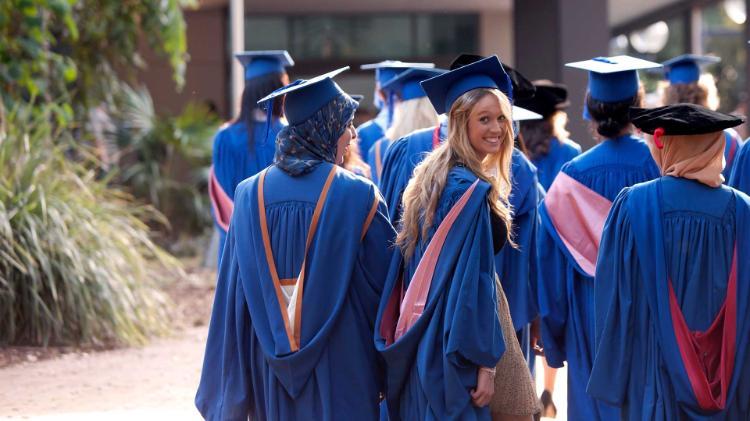 Students walking through campus in graduation gowns