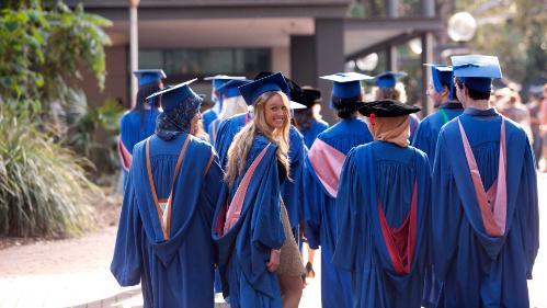 Students walking through campus in their graduation gowns