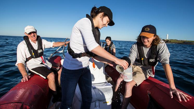 UOW marine biology students on a boat collecting water samples