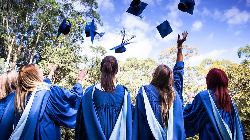 An image of graduates throwing their hats in the air