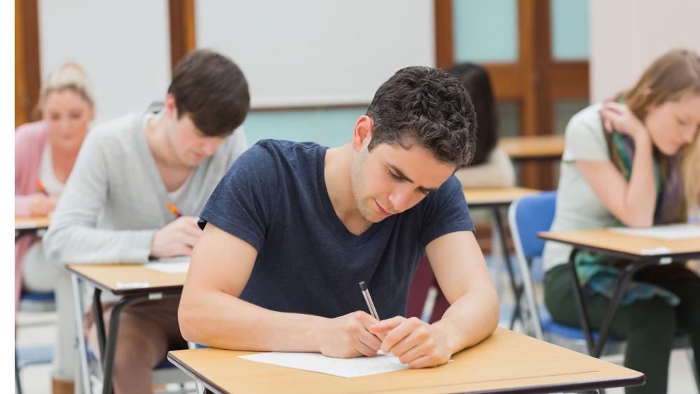 Students sitting a pen and paper exam in a classroom.