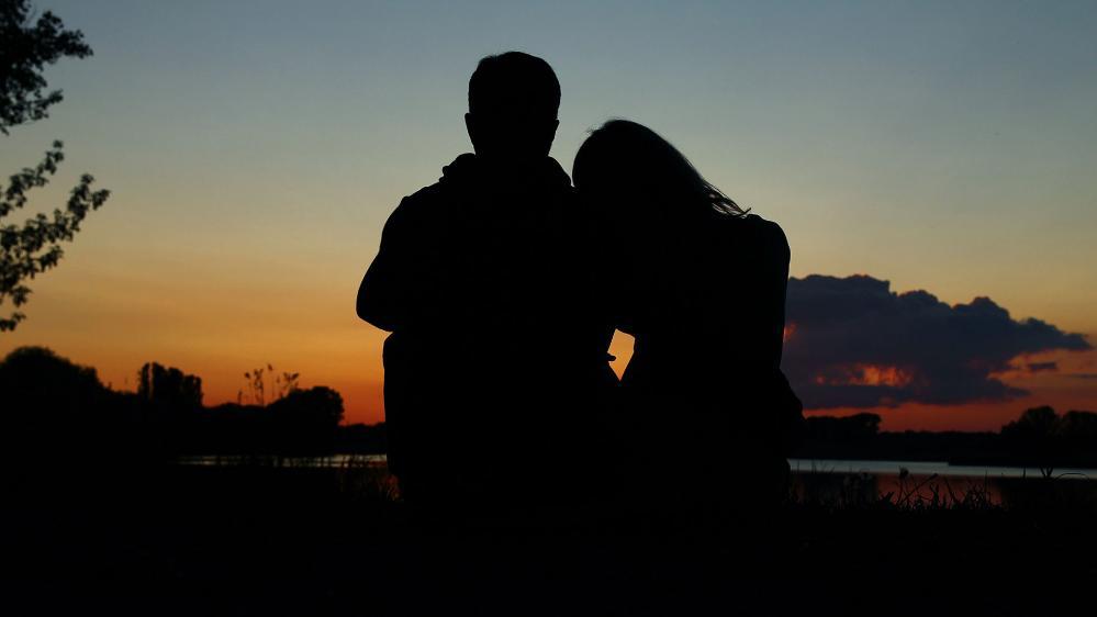 The silhouette of a couple sitting together at sunset.