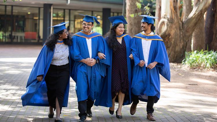 Four students walking in their graduation gown