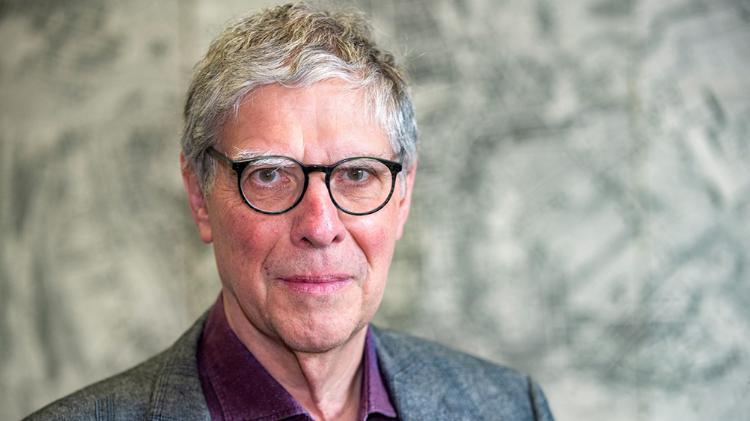 Professor Glenn W. Most wearing eye glasses and a grey jacket with a purple shirt.