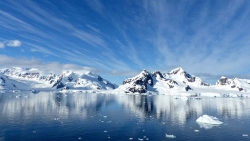 Snow covered mountains of Antarctica, with crystal clear waters in the foreground