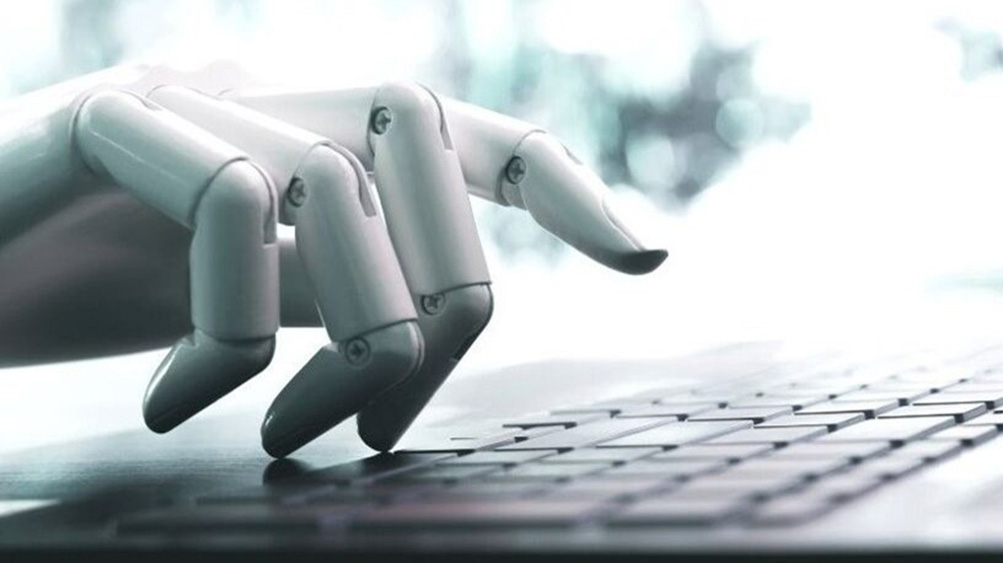 A robotic hand poised over a laptop keyboard, symbolising the fusion of technology and human-computer interaction.