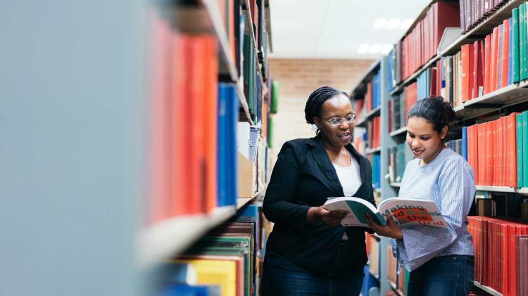 Student and academic in UOW library looking over a book