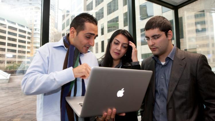 A group of three people looking at a laptop