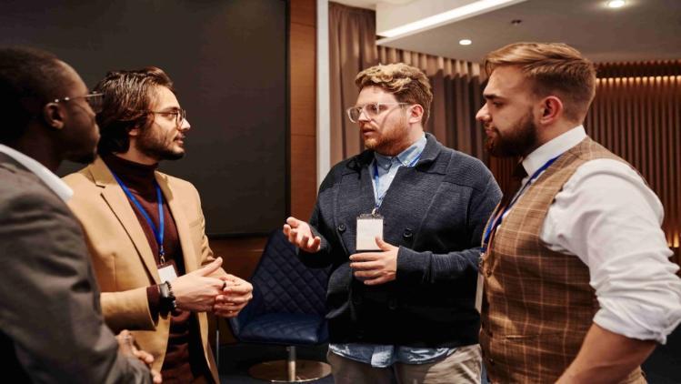 4 men standing at a networking event, having a conversation