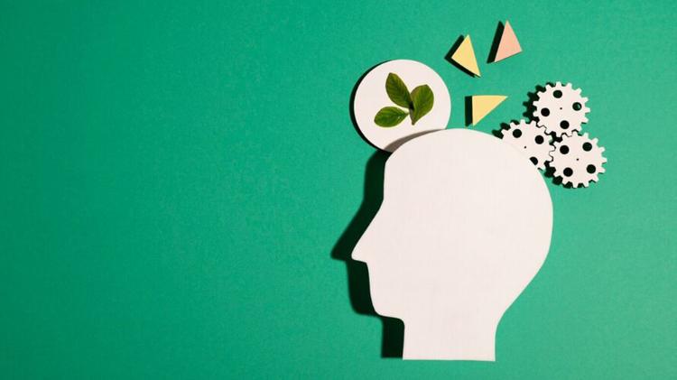 A silhouette of a human head with gears, geometric shapes, and a leaf emerging from the top, set against a green background.