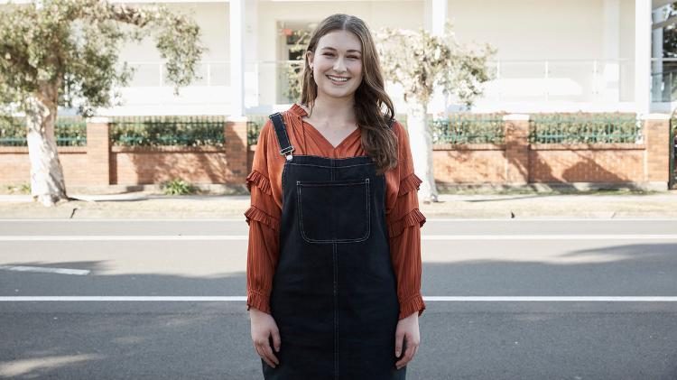 Female student in overalls and orange long sleeve top