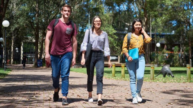 Three students walking on a path at the Wollongong campus