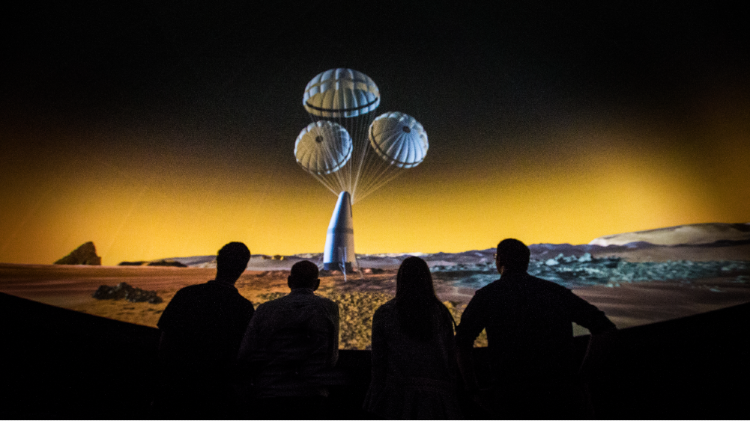 Shadows of people looks at space balloons in a Planetarium.