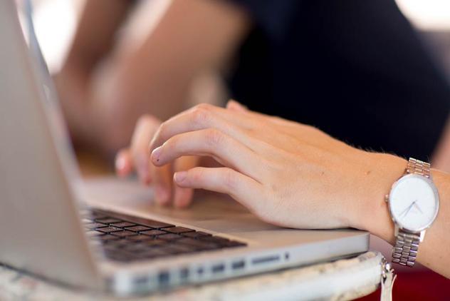 Side view of laptop with womans hands typing