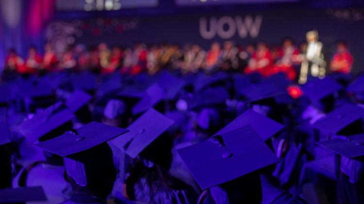 view from behind graduates, looking toward stage