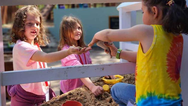 Three girls playing in sandpit