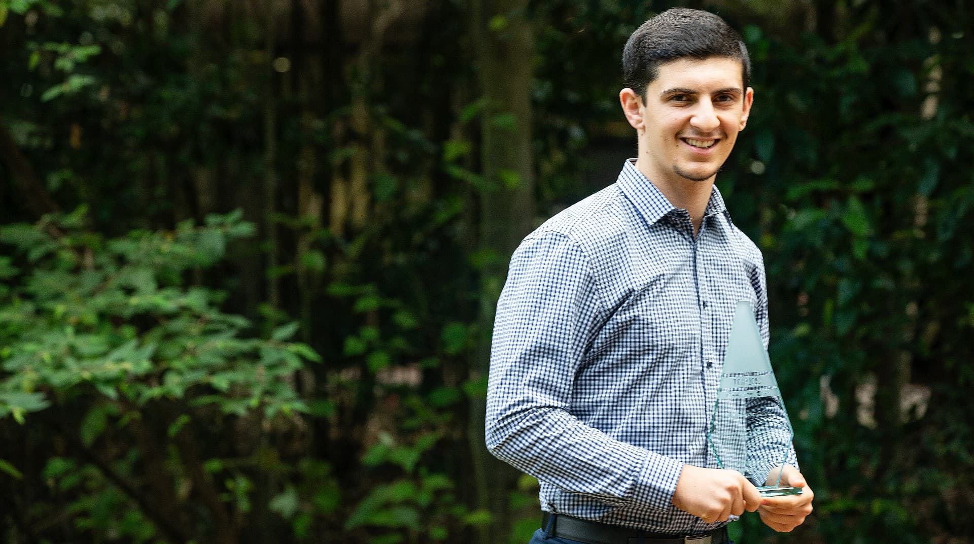 An image of student Adam Karayannis, wearing a blue shirt, among the trees at UOW's Wollongong Campus. Photo: Paul Jones