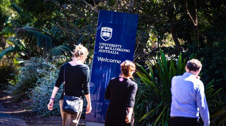 People walking past a University of Wollongong sign