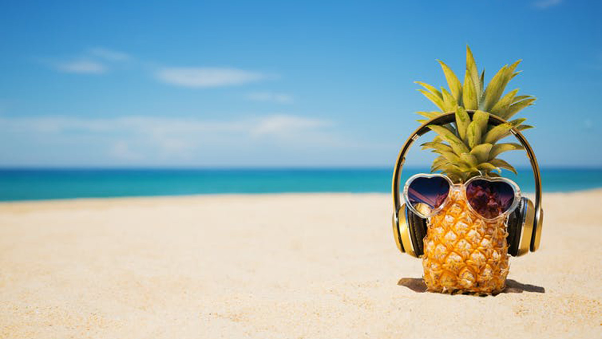 Pineapple on a beach with sunglasses and headphones