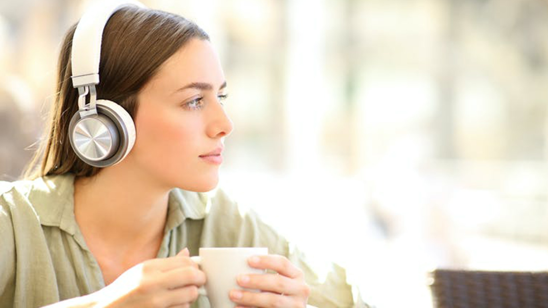 pensive woman wearing wireless headphones relaxing. Shutterstock