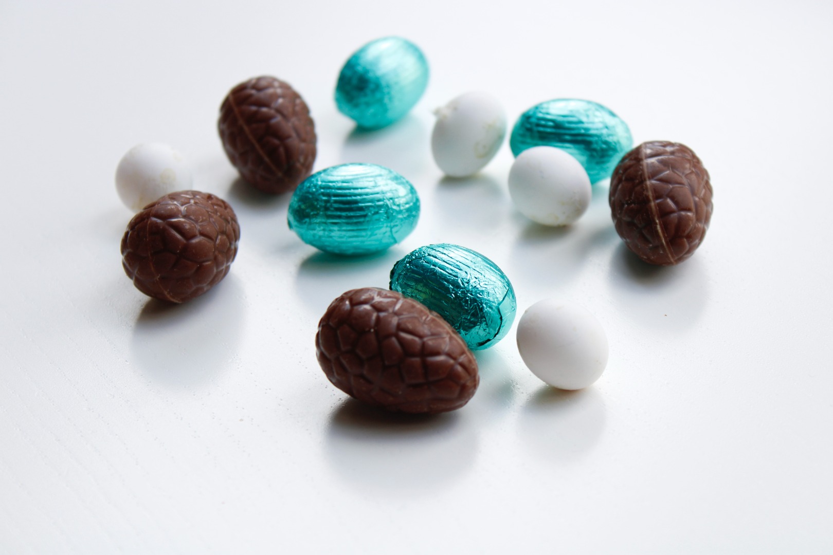 Blue, white and unwrapped Easter eggs against a white background. Photo: Unsplash