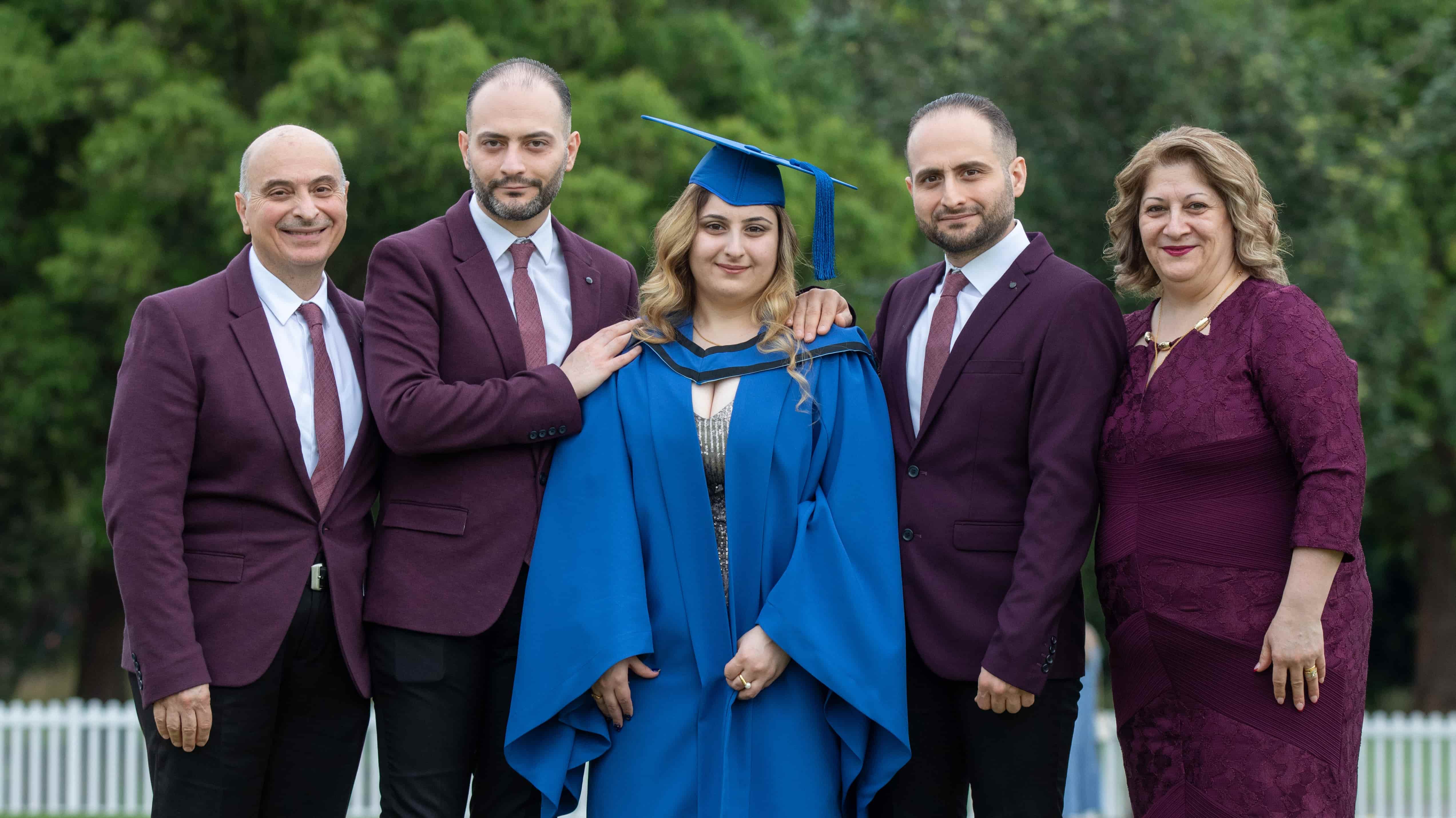 Dawood, Fadi, Lord, Majd and Reem Thabet at graduation day. Lord wears a blue graduation gown and cap, while the rest of the family wear burgundy suits and a dress. They are close together and all smiling. Photo: Andy Zakeli
