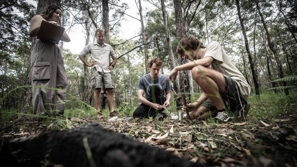 Three students, with Anthony Dosseto watching on, conduct research on the bushland on the NSW South Coast. Photo: Paul Jones