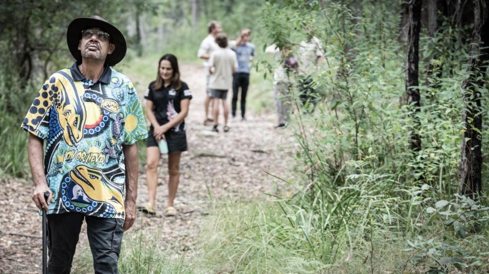 Victor Channel leads the group of researchers in the bush on the NSW South Coast. He has a walking stick and is followed by the team of researchers. Photo: Paul Jones