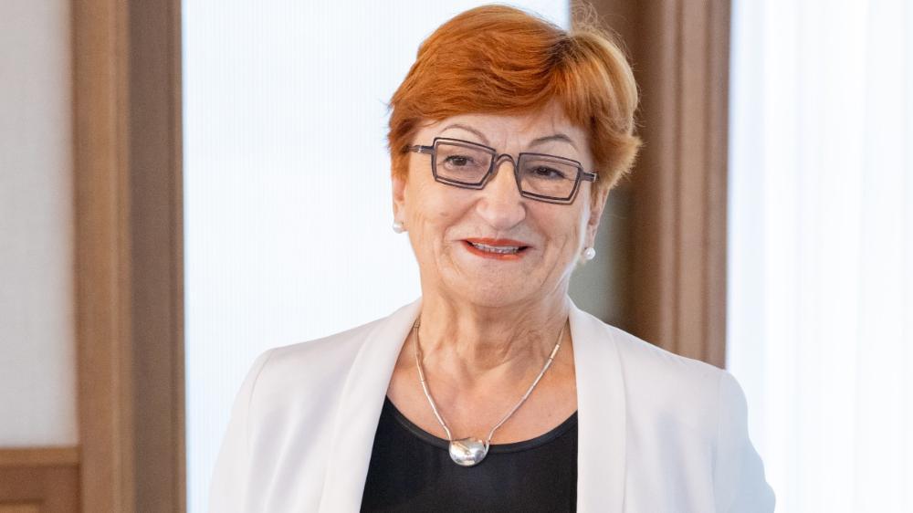 Professor Danica Purg in a close up image. She has red hair, wears black glasses and a white suit. Photo: Simon Kupferschmied