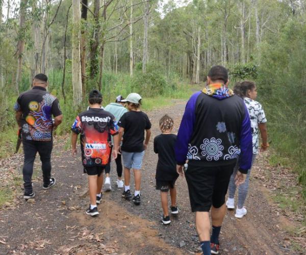 A group of students with mentors from the Koori Kids Culture Club are seen walking into the bush. Photo: Supplied