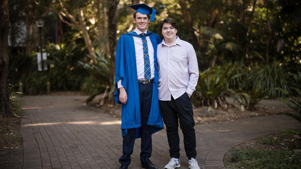 Jackson Cocks, in graduation gown and cap, with his brother Harrison, on Wollongong campus. Photo: Michael Gray