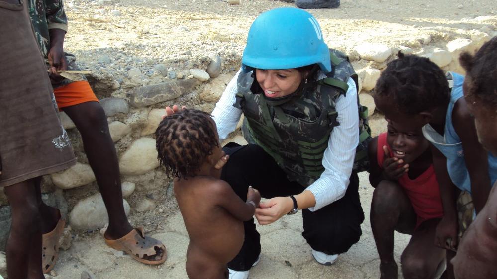 Dr Izabela Pereira Watts, wearing a blue United Nations helmet, talks to a young boy while working as a peacekeeper in Haiti. Photo: Supplied