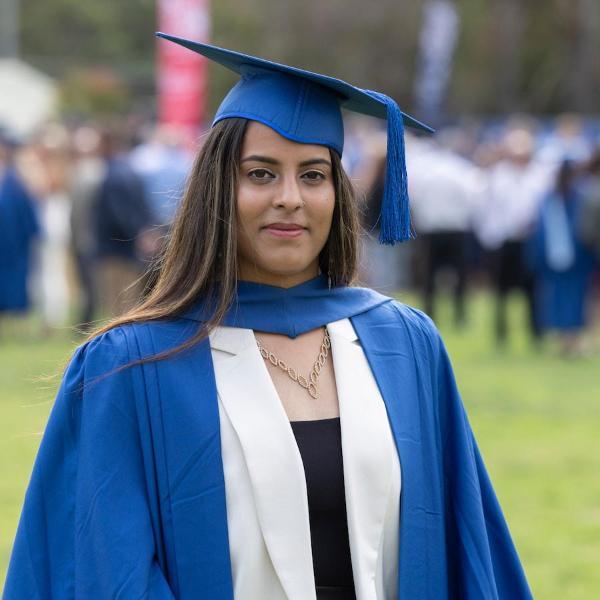 Zinah Hasan wears a blue graduation cap and stares at the camera. Photo: Mark Newsham