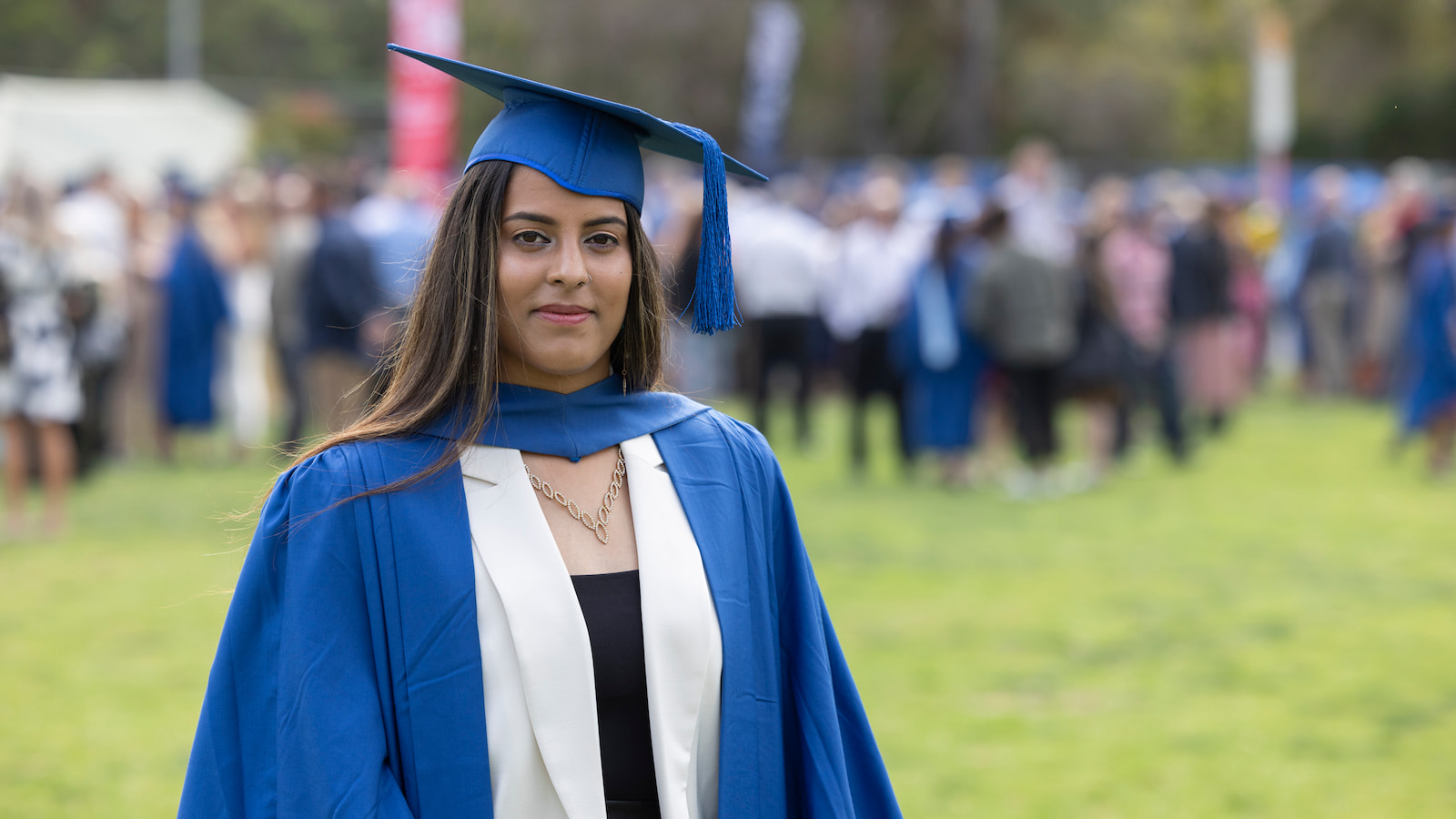 Zinah Hasan wears a blue graduation cap and stares at the camera. Photo: Mark Newsham