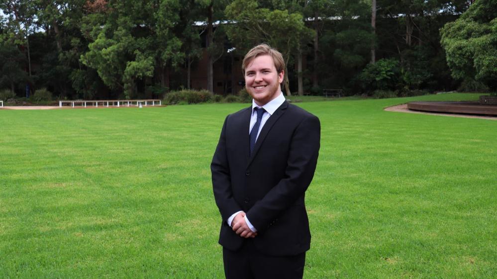 Jacob May stands on a lawn on UOWs Wollongong Campus