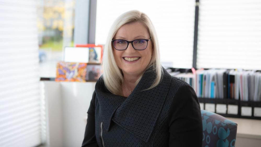 Liesel Wett smiling in front of a UOW sign