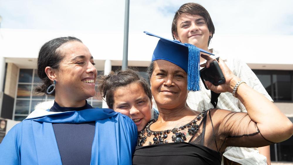 Loureene with her mother and her two boys. Her mother has a graduation cap on her head and the boys are in the background. Photo: Paul Jones