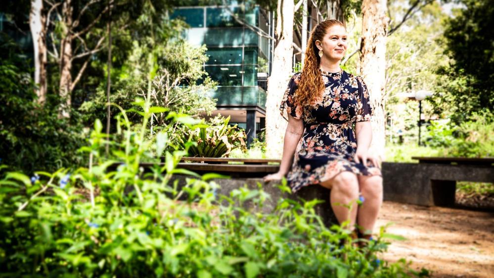 UOW graduate Meg Cummins, pictured standing against a tree at UOW's Wollongong campus. Photo: Paul Jones