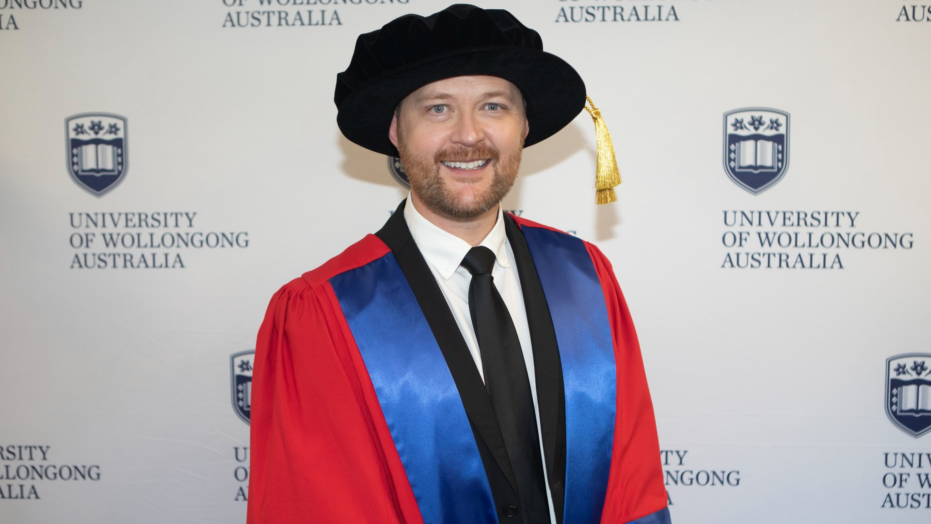 Theatre producer Michael Cassel, pictured against a UOW wall, wearing his graduation gown and cap. Photo: Mark Newsham