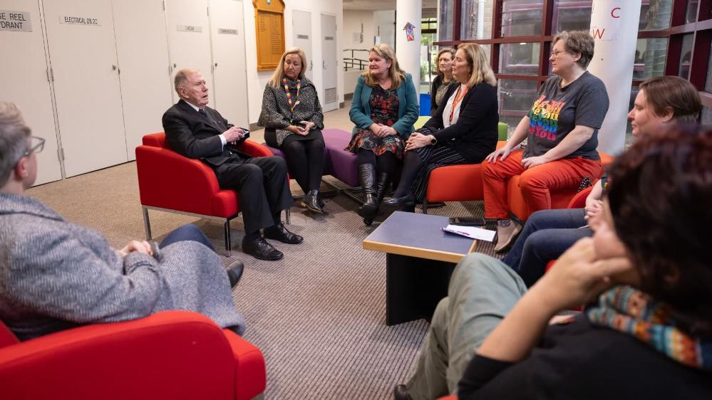 Justice Michael Kirby meets with members of UOWs Ally Network. They sit on red armchairs in a circle.