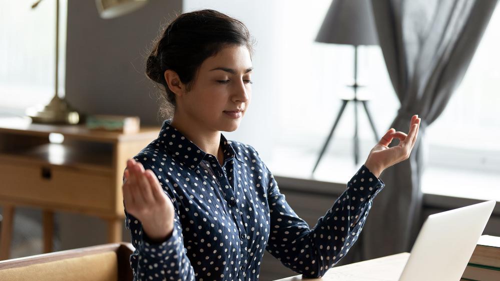 A young woman meditates at her computer